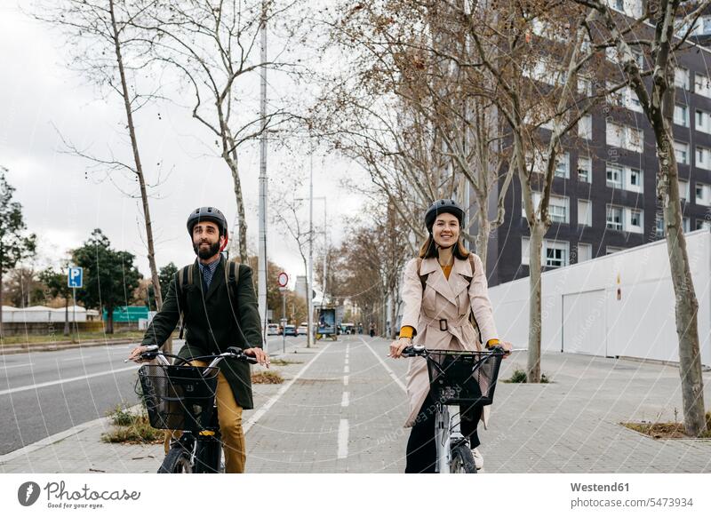 Couple riding e-bikes in the city riding bicycle riding bike bike riding cycling bicycling pedaling E-Bike Electric bicycle Electric Bike town cities towns