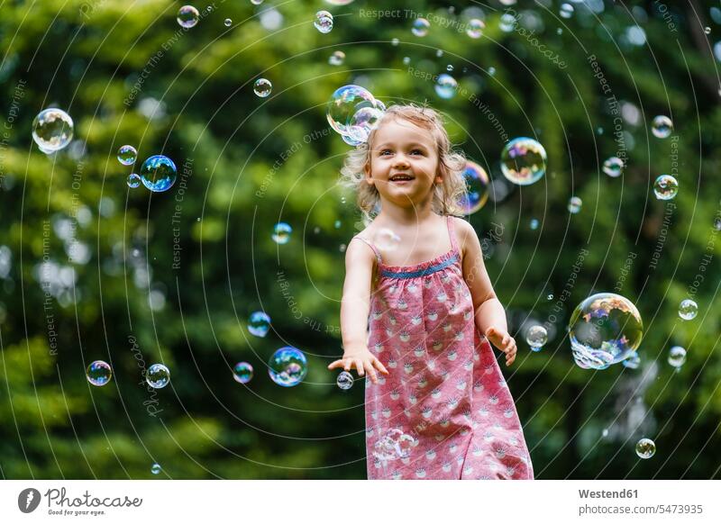 Happy girl enjoying while running amidst bubbles at park color image colour image outdoors location shots outdoor shot outdoor shots day daylight shot