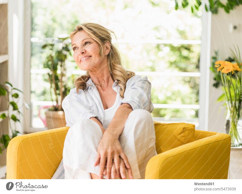 Portrait of smiling mature woman relaxing in armchair at home smile Seated sit delight enjoyment Pleasant pleasure happy colour colours free time leisure time