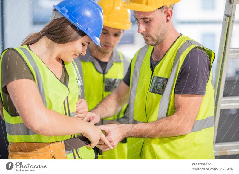 Construction worker helping colleague with tool belt construction site Building Site sites Building Sites construction sites colleagues assistance assisting