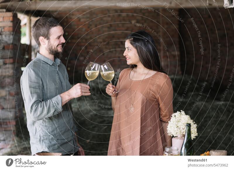 Happy couple toasting cocktail while looking at each other in barn color image colour image indoors indoor shot indoor shots interior interior view Interiors