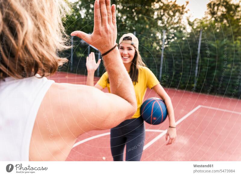 Young man and young woman high-fiving after basketball game fitness sport fairness High Five high fiving Hi-Five High-Five active Basketball exercising exercise