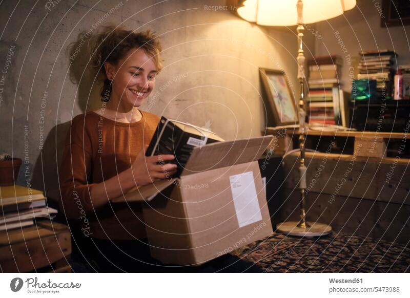 Smiling young woman unpacking parcel at home human human being human beings humans person persons caucasian appearance caucasian ethnicity european 1