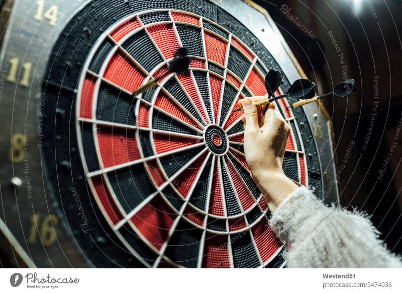 Woman's hand collecting darts from board color image colour image indoors indoor shot indoor shots interior interior view Interiors leisure activity