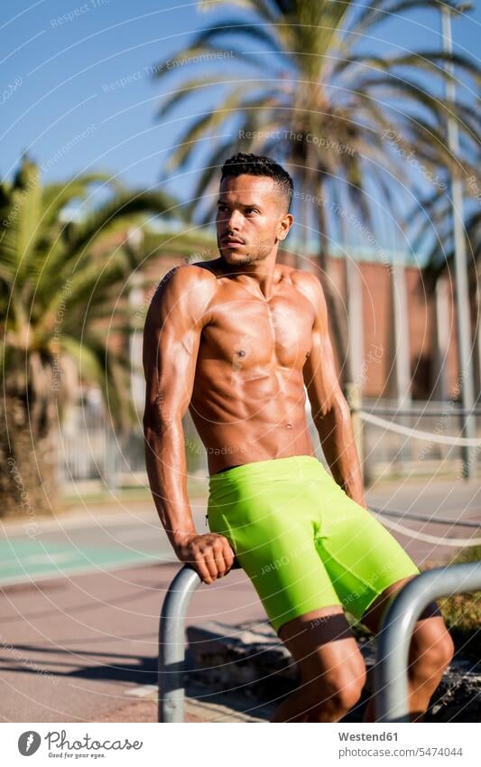 Barechested muscular man exercising outdoors looking around muscles athletic workout working out work out exercise training practising looking round look round