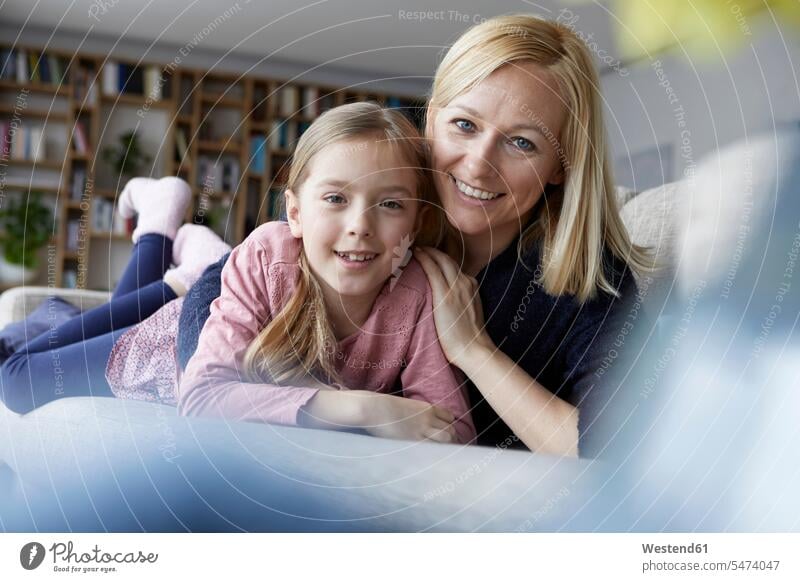 Mother and daughter having fun at home couch settee sofa sofas couches settees daughters mother mommy mothers ma mummy mama lying laying down lie lying down