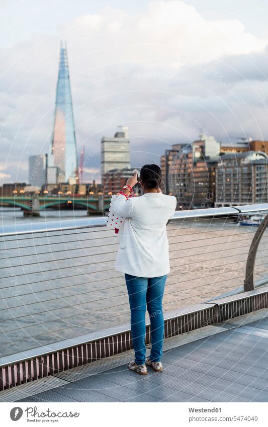 UK, London, woman standing on a bridge taking picture of The Shard females women bridges photographing Adults grown-ups grownups adult people persons