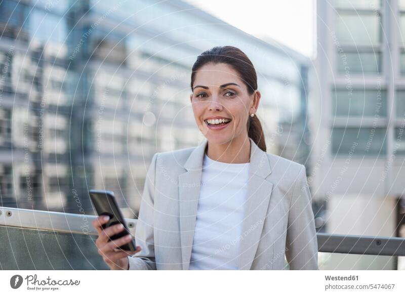 Portrait of smiling businesswoman with cell phone businesswomen business woman business women portrait portraits Smartphone iPhone Smartphones business people