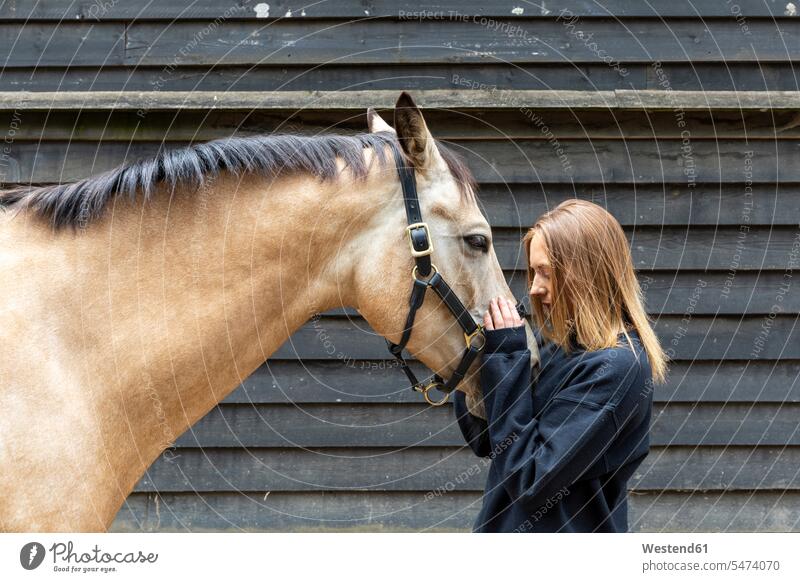 Young woman stroking her horse friends delight enjoyment Pleasant pleasure happy closeness propinquity content Contented Emotion pleased free time leisure time