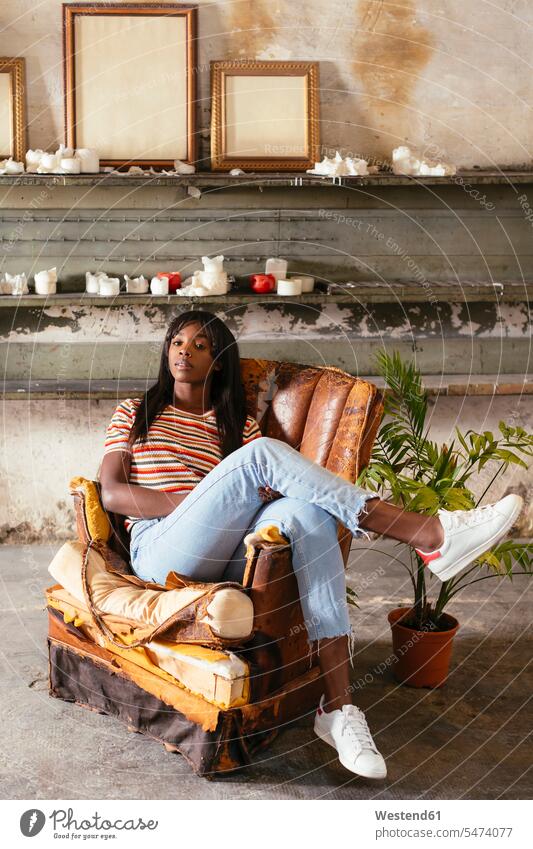 Portrait of cool young woman sitting on an old leather chair in a loft Seated portrait portraits lofts armchair Arm Chairs armchairs females women Adults
