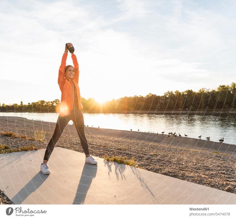 Young woman exercising with a kettlebell at the river young women young woman Kettlebell Kettle bells Kettlebells River Rivers exercise training practising