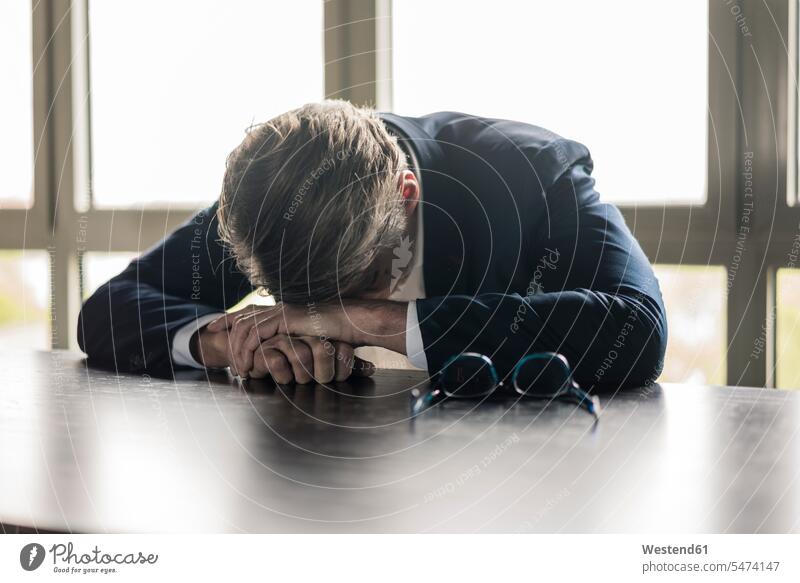 Mature businessman resting his head on the table Table Tables Businessman Business man Businessmen Business men heads business people businesspeople