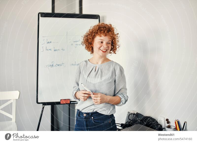 Smiling businesswoman leading a presentation at flip chart in conference room colleague Occupation Work job jobs profession professional occupation