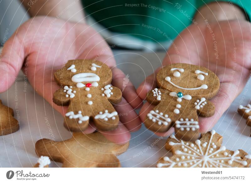 Man's hands holding two different Gingerbread Men, close-up Gingerbread Man gingerbread human hand human hands people persons human being humans human beings