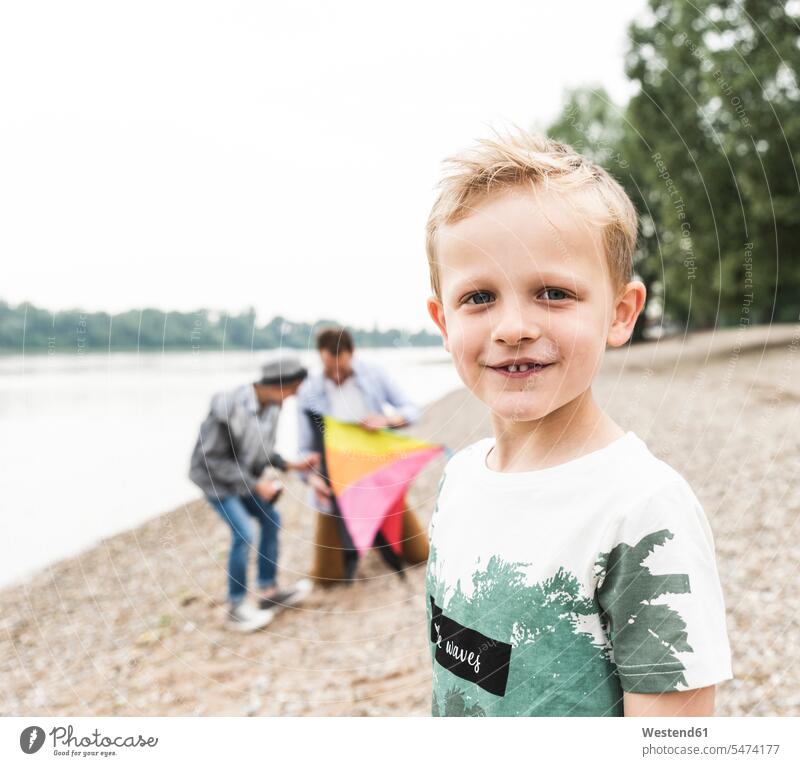 Portrait of smiling boy with father and brother holding kite at the riverside son sons manchild manchildren pa fathers daddy dads papa portrait portraits River