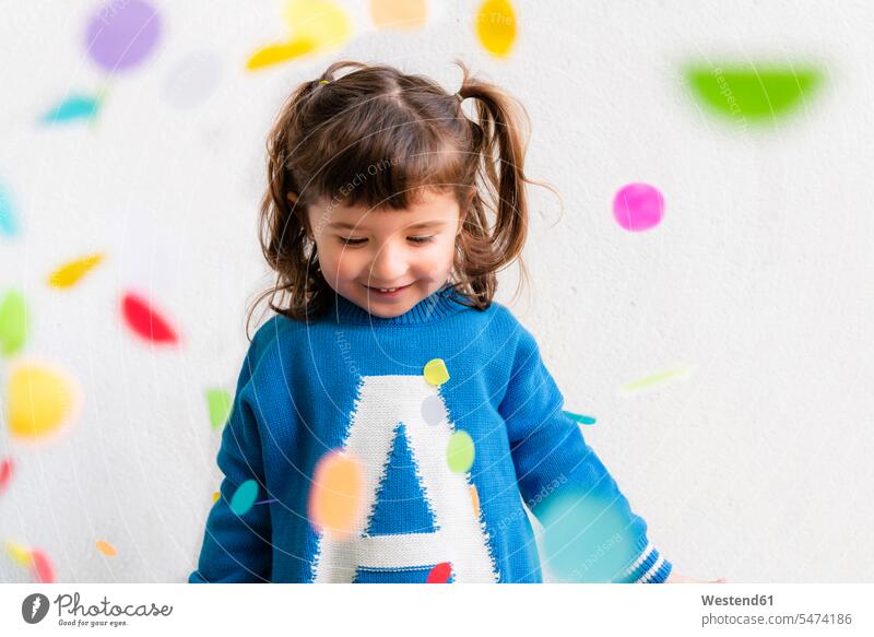 Happy little girl with the confetti during a party in front of a white wall human human being human beings humans person persons caucasian appearance