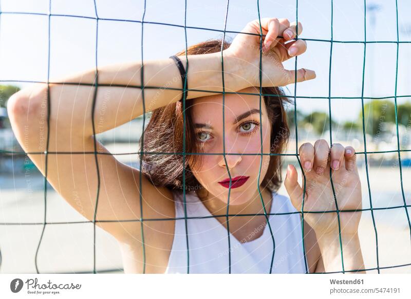 Portrait of young woman behind fence portrait portraits females women city town cities towns fences Adults grown-ups grownups adult people persons human being