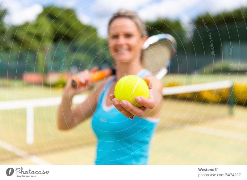 Smiling mature woman holding a tennis ball at tennis club human human being human beings humans person persons caucasian appearance caucasian ethnicity european