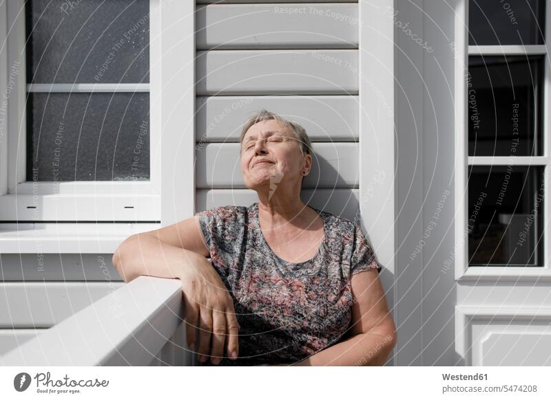 Relaxed senior woman sitting on porch in sunshine Germany resting flat flats apartment apartments getting away from it all Getting Away From All unwinding