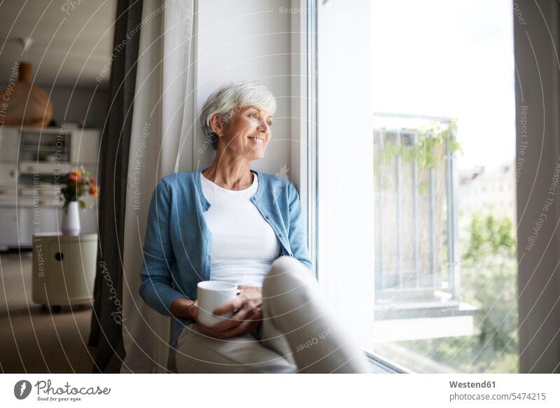Senior woman looking out of window while sitting at home color image colour image indoors indoor shot indoor shots interior interior view Interiors day