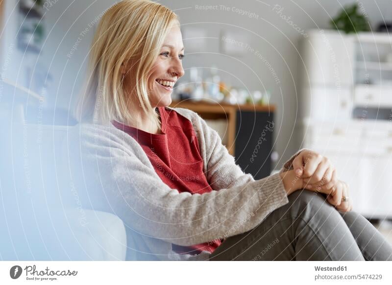 Happy woman relaxing at home laughing Laughter smiling smile sitting Seated mature woman mature women positive Emotion Feeling Feelings Sentiments Emotions