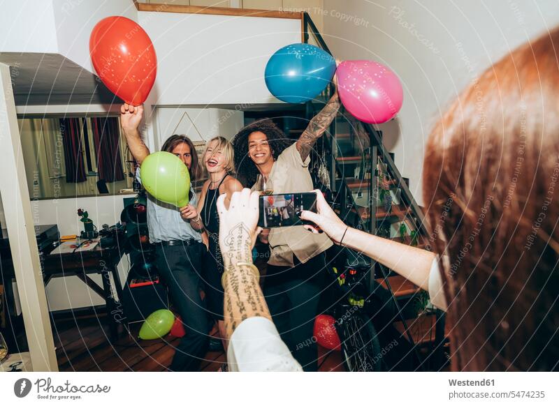 Woman photographing friends dancing during party at home color image colour image indoors indoor shot indoor shots interior interior view Interiors