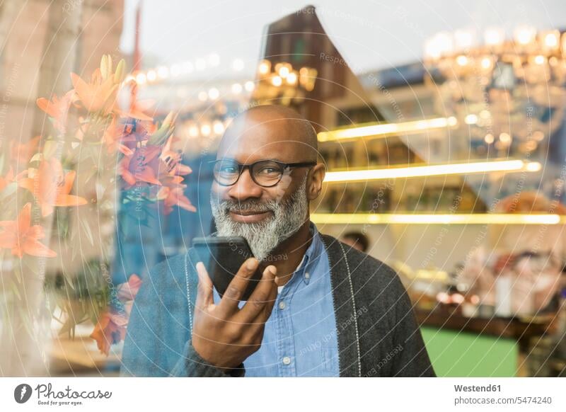 Portrait of smiling man with cell phone behind windowpane window glass window glasses windowpanes Window Pane Smartphone iPhone Smartphones smile portrait