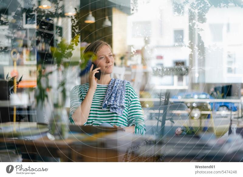 Smiling young woman on cell phone in a cafe females women smiling smile mobile phone mobiles mobile phones Cellphone cell phones on the phone call telephoning