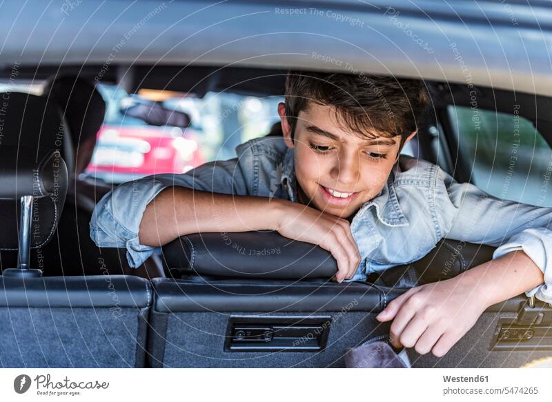 Smiling boy in car looking in boot smiling smile boys males automobile Auto cars motorcars Automobiles eyeing child children kid kids people persons human being