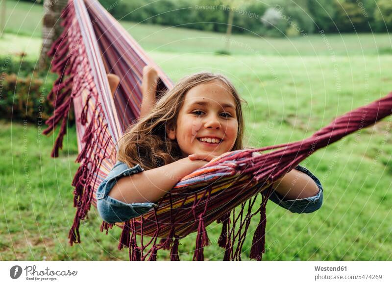 Portrait of happy girl lying in hammock hammocks females girls smiling smile portrait portraits laying down lie lying down happiness child children kid kids