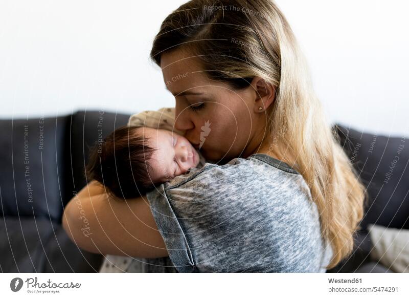 Mother holding and kissing her newborn baby multicultural happiness happy eyes closed closed eyes Eyes Shut together Care caring care home at home positive