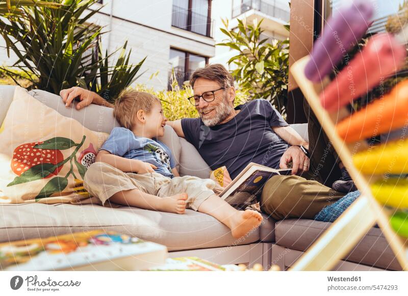 Father and son reading a book on their terrace books T- Shirt t-shirts tee-shirt couches settee settees sofa sofas smile seasons summer time summertime summery