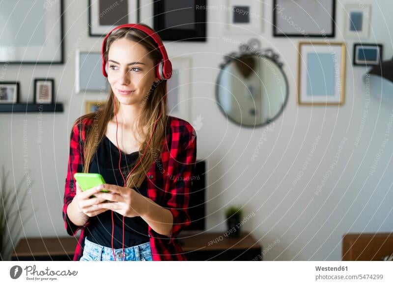 Young woman with cell phone and headphones at home human human being human beings humans person persons celibate celibates singles solitary people