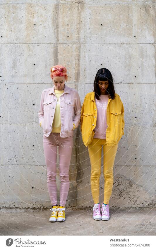 Two alternative friends having fun, wearing yellow and pink jeans clothes, looking down female friends posing pose Posed homosexual queer same-sex homosexually