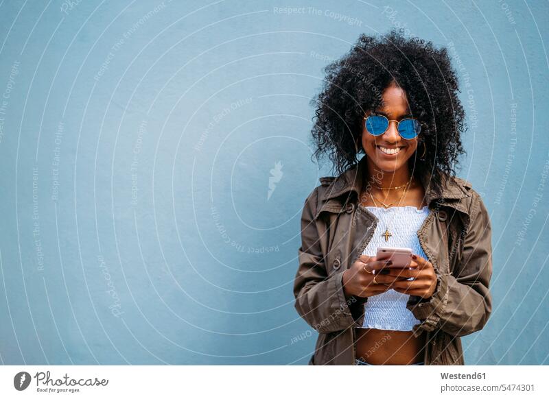 Woman using smartphone, blue background telecommunication phones telephone telephones cell phone cell phones Cellphone mobile mobile phones mobiles hold read