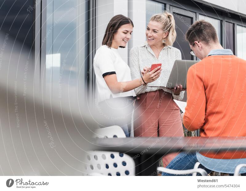 Casual business people with smartphone and laptop meeting on roof terrace human human being human beings humans person persons caucasian appearance