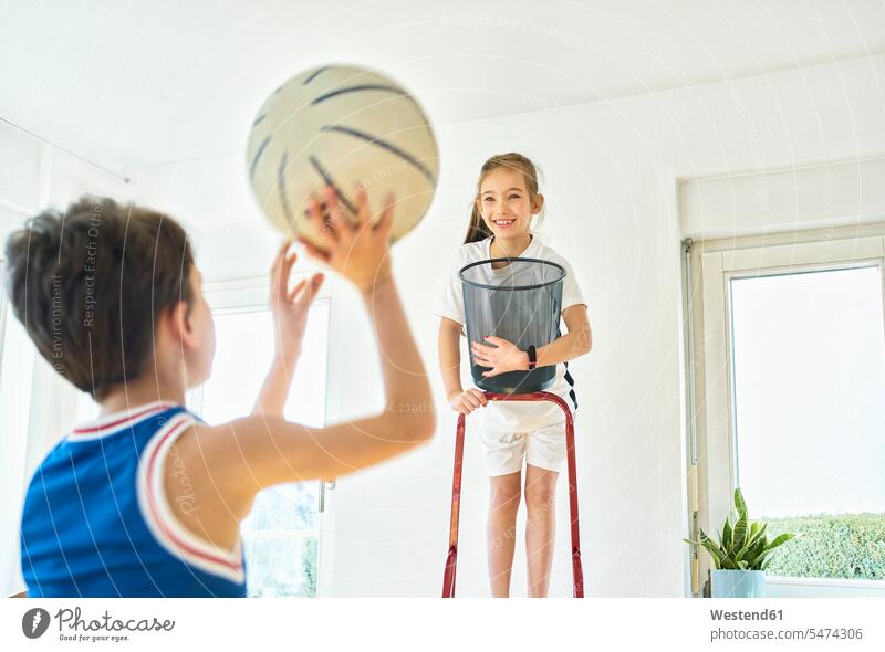 Boy and girl playing basketball at home windows ladders balls hold smile delight enjoyment Pleasant pleasure Cheerfulness exhilaration gaiety gay glad Joyous