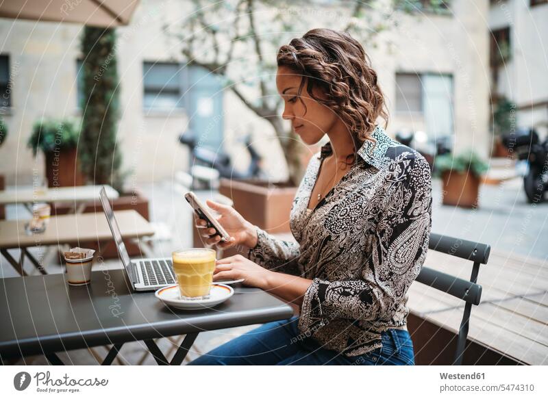 Young woman using laptop and smartphone at a pavement cafe Occupation Work job jobs profession professional occupation business life business world