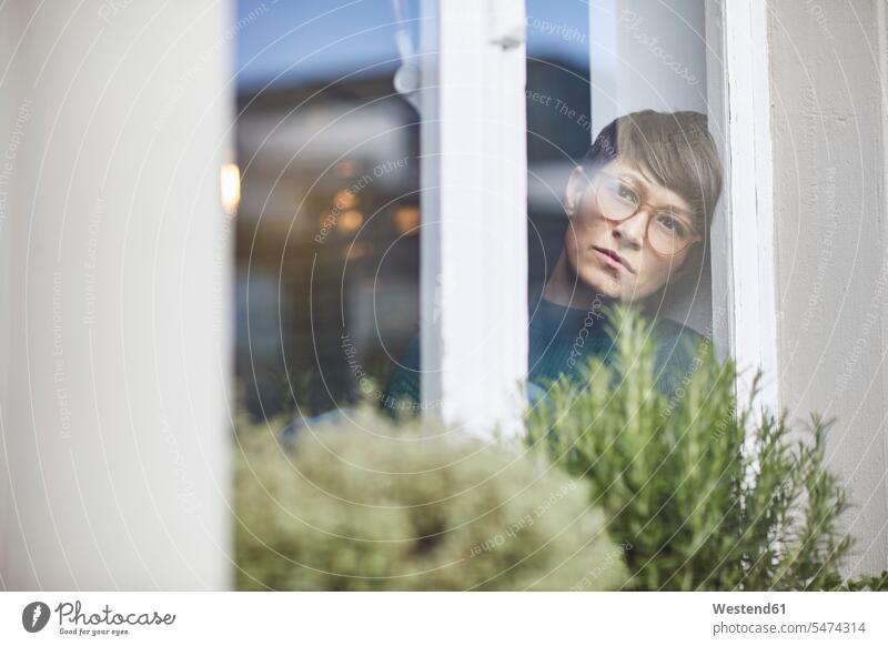 Pensive woman at home looking out of window human human being human beings humans person persons celibate celibates singles solitary people solitary person