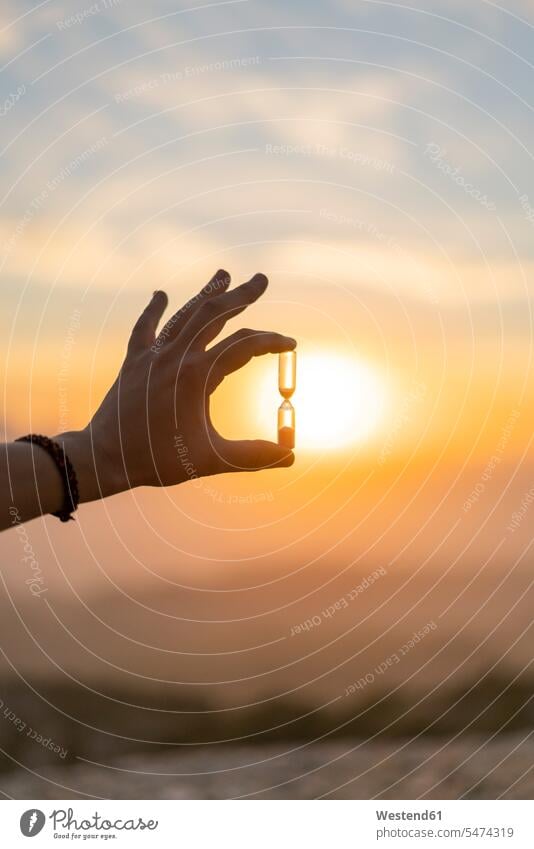 Close-up of man's hand holding an hourglass at sunset Hourglass Sand Glass Hourglasses Hour Glass Hour Glasses Sand Glasses sunsets sundown human hand hands