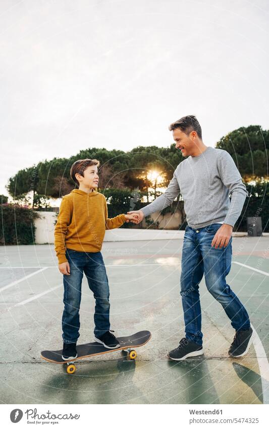 Father assisting son riding skateboard Skate Board skateboards father pa fathers daddy dads papa sons manchild manchildren assistance Help helping parents