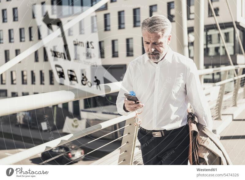 Mature businessman using cell phone for navigation in the city human human being human beings humans person persons caucasian appearance caucasian ethnicity
