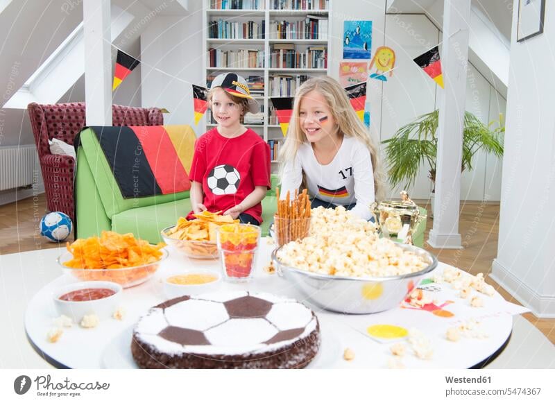 Brother and sister watching football world cup with sweets and snacks home at home friends soccer flag flags munchies nibbles together Football World Cup