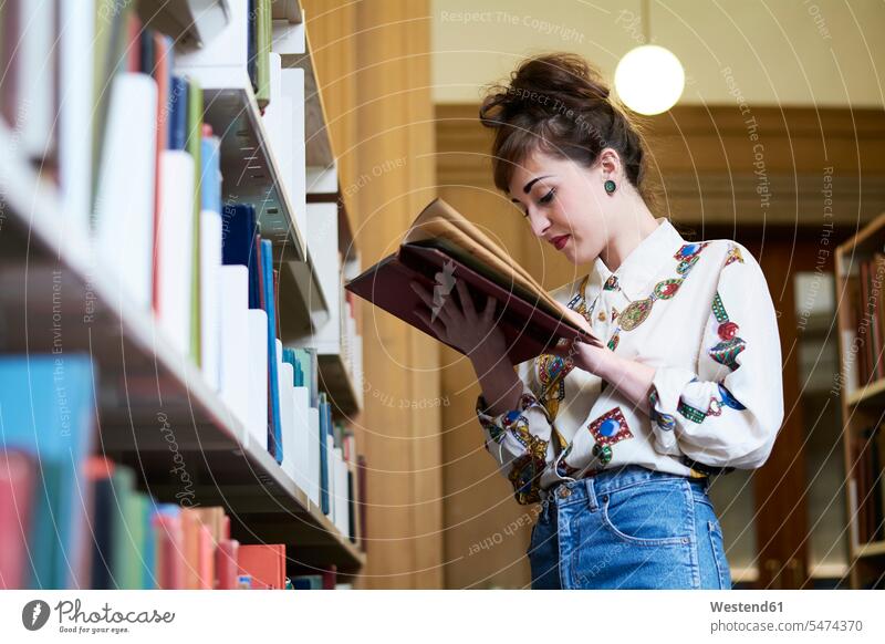 Female student reading book in a public library female students woman females women books looking down bookworm higher education Adults grown-ups grownups adult