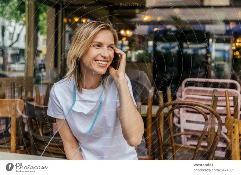 Portrait of woman on the phone with protective mask in front of a closed coffee shop windows pane panes window glass window glasses Window Pane windowpanes band