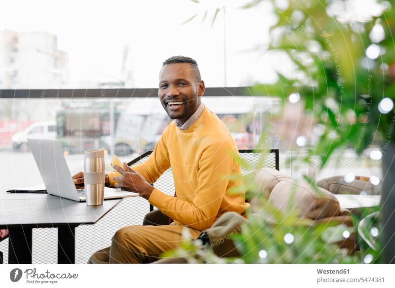 Portrait of a happy man with smartphone and laptop in a cafe Occupation Work job jobs profession professional occupation business life business world