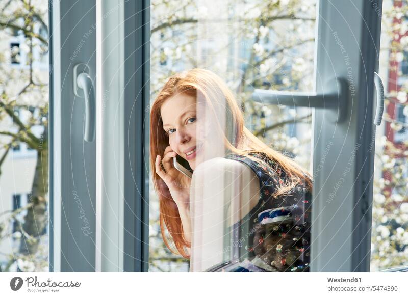 Portrait of redheaded woman on the phone leaning out of window in spring portrait portraits windows red hair red hairs red-haired call telephoning