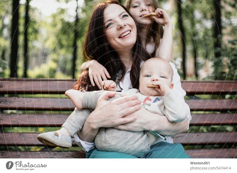 Smiling mother with her two kids eating cookies in the park human human being human beings humans person persons caucasian appearance caucasian ethnicity