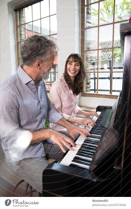 Mature couple having fun at home, playing the piano Fun funny twosomes partnership couples pianos together people persons human being humans human beings music