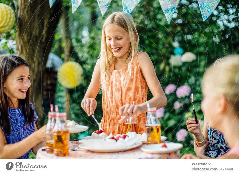 Girl dishing up cake on a birthday party outdoors friends mate female friend Bottles decorating decorations Tables smile seasons summer time summertime summery